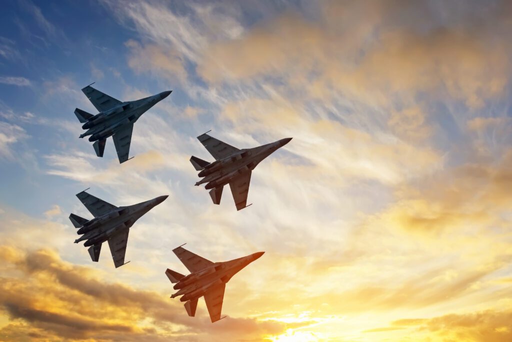 Four fighter jets in the shape of a diamond in a sunsetting sky.