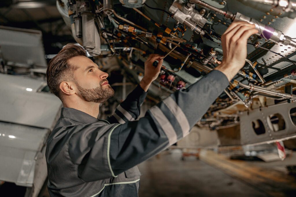 A man looks at the open engine compartment of an airplane.